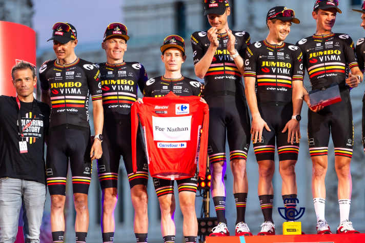 Jumbo-Visma beendete die Vuelta Espana 2023 nicht nur auf den ersten drei Plätzen in der Gesamtwertung im Einzel, sondern damit auch als bestes Team. Bei der Siegerehrung in Madrid präsentierte das Team ein Trikot als Hommage für Nathan Van Hooydonck.