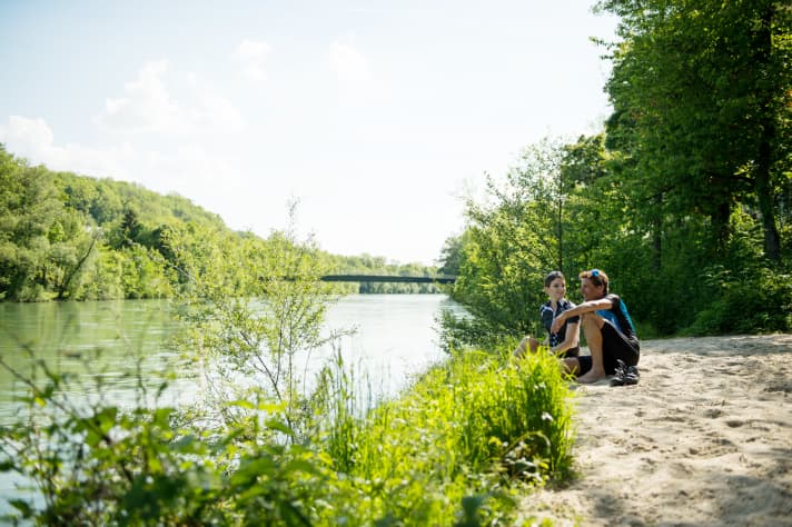 A couple taking a break on the banks of the Traun with a view of the river on a road bike ride.