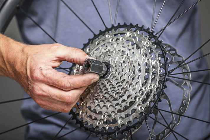 Zahnkranzabzieher gibt’s als Nuss, wie hier im Bild,  oder komplette Schlüssel. Wichtig: Auf Kompatibilität zu Freilauf bzw. Kassette achten.