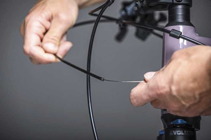 The fresh outer cover is threaded onto the Bowden cable from the front and guided through the frame.