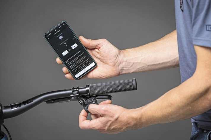 Die AXS-Taste mit dem Zeigefinger gedrückt halten, dann kann der Schaltkäfig über die zwei Haupttaster nach links und rechts justiert werden. Die App zeigt an, in welcher Micro-Adjust-Position das Schaltwerk steht. 7 zeigt die neutrale Mittelposition.