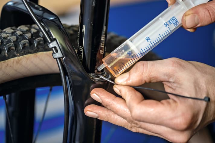 Top up fork oil with caution: The coating of the fork must not be scratched! A plastic cable tie prevents this.
