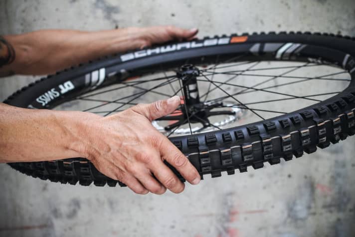   Fig. 7: Check fit, shake: Finally, check that the tyre is seated correctly to ensure perfect function. The guide line on the sidewall of every tubeless tyre is used for this purpose. It should be the same distance from the rim everywhere. This ensures that the tyre does not become unbalanced and sits correctly in the rim flange. If necessary, help by increasing the air pressure until the tyre sits evenly everywhere. Caution: The maximum pressure of the tyre and rim should not be exceeded. Finally, shake the wheel at right angles to the direction of travel so that the sealant is optimally distributed in the tyre.  This ensures that the tyre is completely sealed.