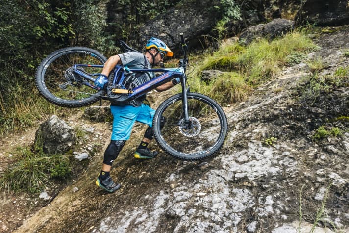   Bei abschüssigen und eventuell ausgesetzten Trage­passagen tragen Sie das Bike seitlich. Die Sattelspitze klemmt dann am Gurtband des Rucksacks (5) – das ist weniger schmerzhaft. Wichtig: Vario-Stütze ganz ausfahren!