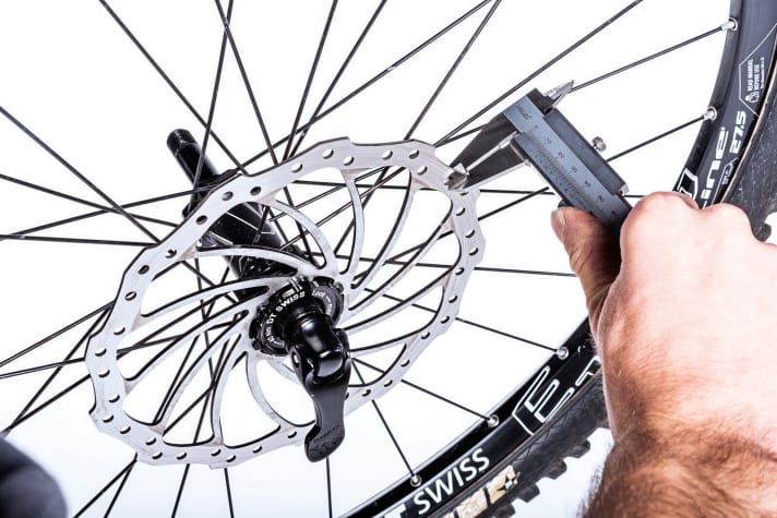    7 Scheibendicke kontrollieren: Bevor Sie das Laufrad wieder einsetzen, messen Sie die Mindeststärke der Bremsscheibe. Diese beträgt bei Magura 1,8 mm. Exakt bestimmen können Sie die Mindeststärke nur mit einer Schublehre. Bei Unterschreiten dieses Wertes ist die Bremsscheibe zu tauschen. Ebenso, wenn die Schreibe deutliche Riefen aufweist. 
