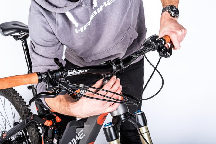    Steuersatz-Check: Nicht nur bei normalen Bikes ist der Steuersatz ständig unter Druck. Durch das etwas höhere Eigengewicht legen E-Mountainbikes hier sogar noch einen drauf! Ist das Bike zu lange mit Steuersatzspiel im Einsatz, können die Lager auf Dauer Schaden nehmen. Deshalb gilt: Kontrollieren Sie den Steuersatz regelmäßig auf Spiel und stellen Sie ihn bei Bedarf nach.     1 Spiel prüfen: Bei gezogener Vorderbremse legt man die Finger um Steuerrohr und oberen Lagerdeckel und schiebt das Bike gegen den Bremswiderstand nach vorne und zurück. Lagerspiel wird hier in der Regel sofort spürbar. Natürlich können Sie dasselbe auch am unteren Lager prüfen.  