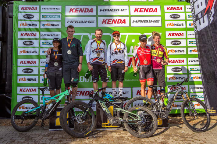   Das Podium der ersten Deutschen E-Bike Meisterschaft in Wipperfürth. Herren: 1. André Kleindienst, 2. Till Jungmann, 3. Jochen Käß. Damen: 1. Kim Schwemmer, 2. Martina Wunderle, 3. Stefanie Rickfelder