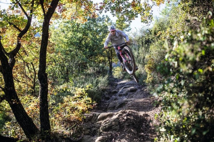   Fabien Barel hat offensichtlich keine Probleme, das schwere E-MTB in der Luft zu bewegen. Mühelos überfliegt der ehemalige Downhill-Weltmeister eine haarige Felspassage auf seiner Hausstrecke.