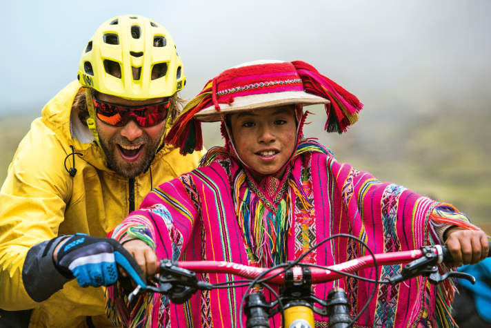   Wer hat hier mehr Spaß? Beim Besuch einer Dorfschule verteilen wir Verpflegung. Begehrt: die Gratis-Runde auf dem Enduro-Bike. Wir müssen schieben, denn die Beine sind noch zu kurz.