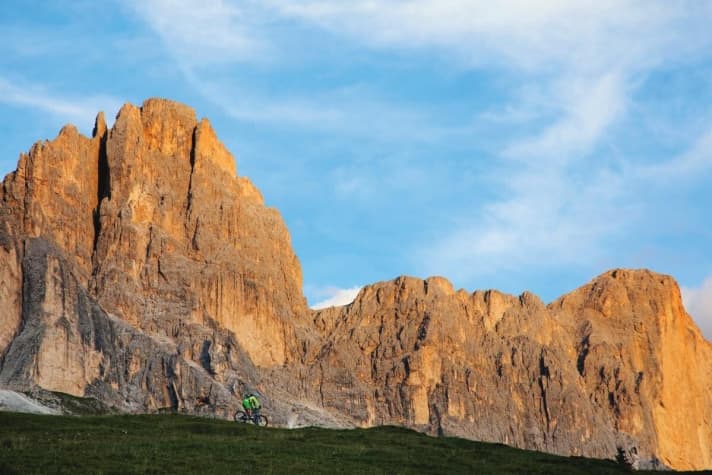   Biking in the fairytale Dolomites: in front of the shimmering red and yellow rock face of the Rosengarten.