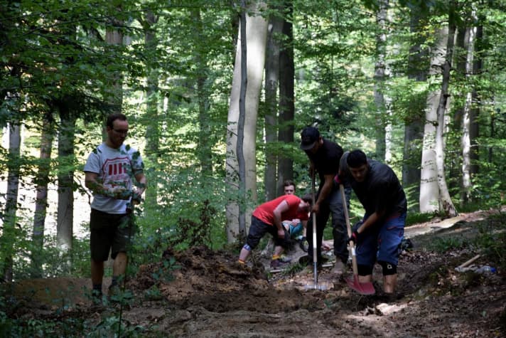   Trail building pro Eric (second from left, black cap) shows how it's done. Club members lend a hand shovelling the new trail into shape.