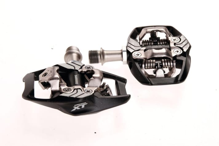 The <a href="https://www.awin1.com/cread.php?awinmid=11768&awinaffid=471469&clickref=B+Shimano+XT+Trail&ued=https%3A%2F%2Fwww.rosebikes.de%2Fshimano-spd-pd-m8120-deore-xt-pedalsatz-2678826" target="_blank" rel="noopener noreferrer nofollow">Shimano XT Trail</a> * is the classic among robust clipless pedals, but the competition never sleeps. Tested against Shimano: six models with an enlarged footprint.
