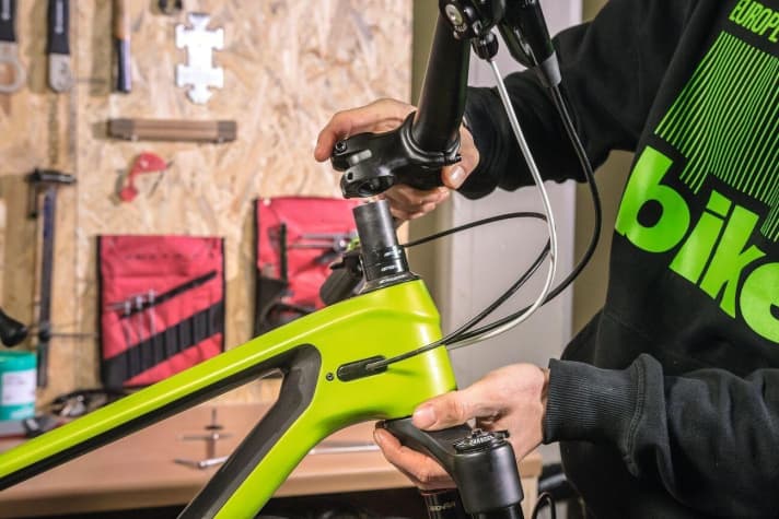 The stem can now be removed from the steerer tube and the fork from the head tube. While working on the headset, the handlebars dangle from the brake and gear cables. Much better: Fix the handlebars/stem to the main frame with string, adhesive tape or cable ties. When pulling the fork out of the main frame, the first headset parts can already be removed.