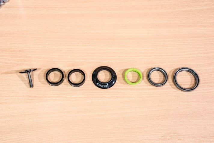 Once the fork has been removed from the main frame, remove the headset parts one by one and place them in the correct order. This way you will know how to reinstall the parts later. Our headset consists of (from left): end cap, centring ring, upper and lower bearing. The fork cone remains on the fork. The components of other headsets may vary.