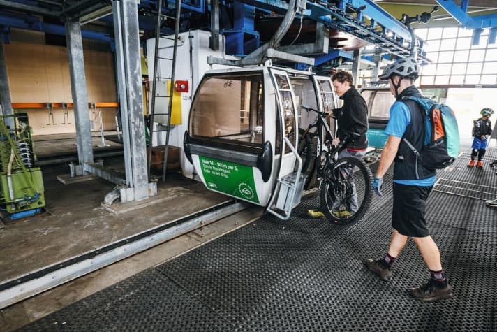   Das Bike wird dem Biker vom Liftpersonal in die Gondel geschoben.