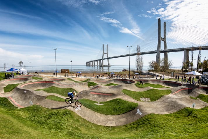   Lissabon, Portugal: Mit direktem Blick auf die weltberühmte Vasco-da-Gama-Brücke und die Strände des Antlantiks befindet sich der Pumptrack in Lissabon. Da macht das Biken auf der 300 Meter langen Strecke gleich doppelt Spaß. Das Red Bull Event findet hier am 6. Juni 2021 statt.