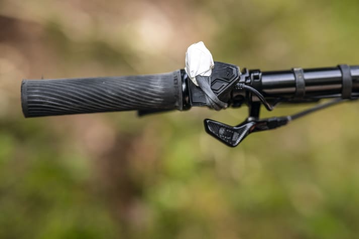   100 % ergonomisch: Der MacGyver-Trick mit einem Stück Fahrradschlauch und einem eingetapten Kieselstein. Diese Idee sparte dem Autor dieses Tests auf einer Alpenüberquerung viel Kraft und Nerven. Bei Bedarf einfach über die Bosch-Kiox-Bedieneinheit gezogen und den Schiebehilfenschalter blockiert, hat man freie Wahl bei der Griffposition. Sicher gibt es aber auch andere McGyver-Lösun­­gen – der Krea­tivität sind hier keine Grenzen gesetzt.