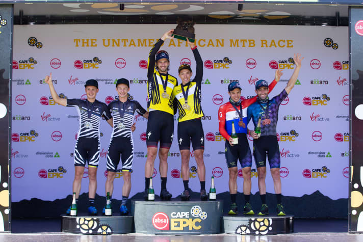   The final podium at the Cape Epic 2021: NinetyOne-songo-Specialized at the top, on the left the Bulls team with Simon Stiebjahn and Martin Frey in second place and on the right the third-placed duo from Buff Scott.