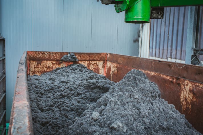A container with textile fibres that are recovered during the recycling process