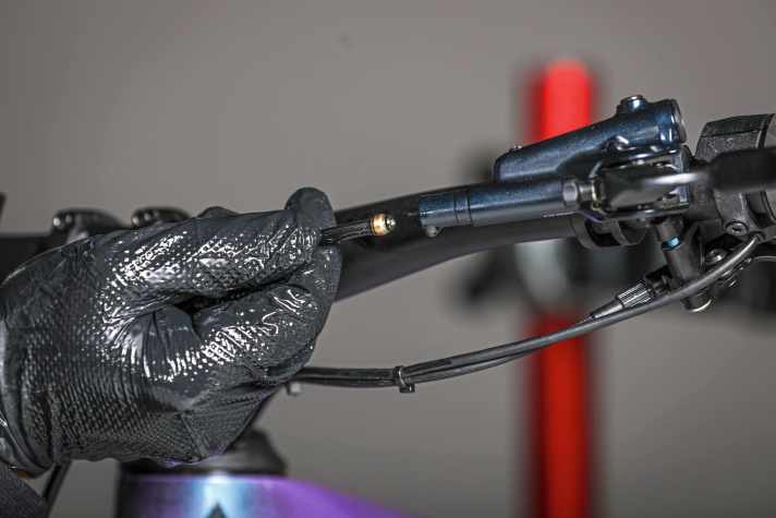 Then carefully remove the line from the brake lever. Keep the bleed screw closed. This reduces oil leakage.