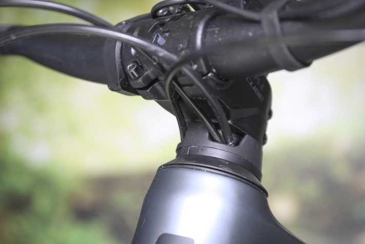 Die Züge laufen optisch elegant durch einen hohen Spacer und den Steuersatz in den Carbon-Rahmen. Das hebt das Cockpit an. Auch der steile Vorbau bockt die Front auf, dadurch liegt der Lenker hoch. Nachteil der Integration: Service- und Schrauberarbeiten werden komplexer.