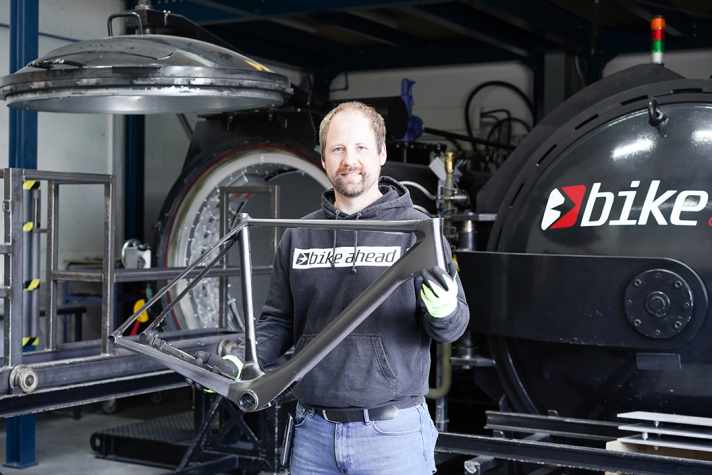 Le chef de Bike-Ahead, Christian Gemperlein, montre fièrement le cadre littéralement tout juste sorti du four. L'entreprise tire au sort le cadre n° 001 parmi tous ceux qui ont participé à ses enquêtes.