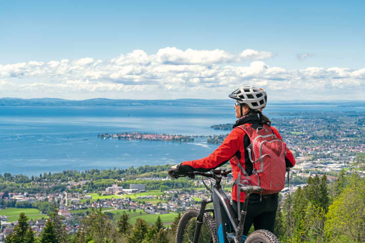 In der Ferne erblickt diese Radfahrerin vom Bodenseeufer die Schweizer Berge.