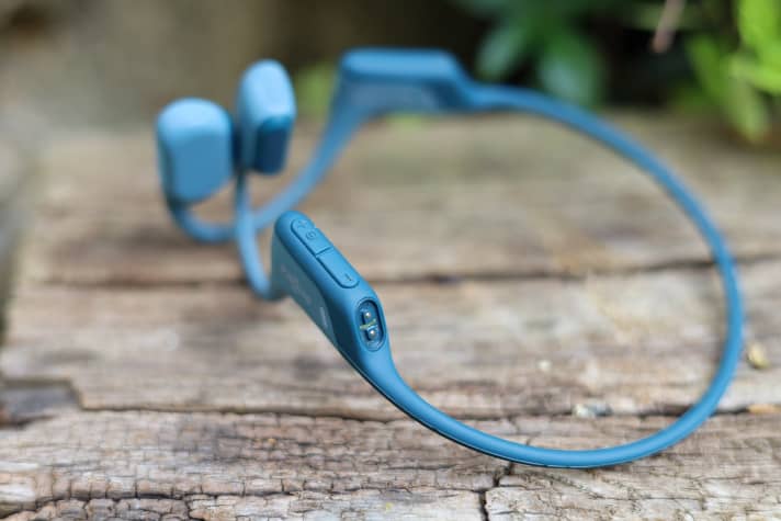 The volume control and a magnetic charging socket are located behind the right ear.