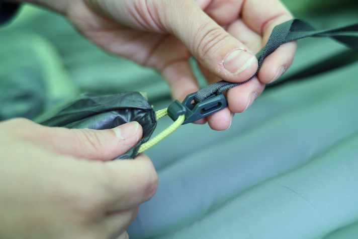 Längenverstellbare, schmale Gurte helfen beim Fixieren des Quiltes um die Isomatte herum. Mit etwas Übung gelingt das selbst müden Radreisenden schnell.