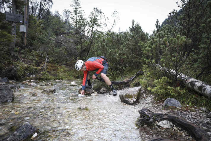 Unscheinbar quillt die berühmte Isar hier aus der Böschung. Ein Schluck Quellwasser geht mit auf Tour.