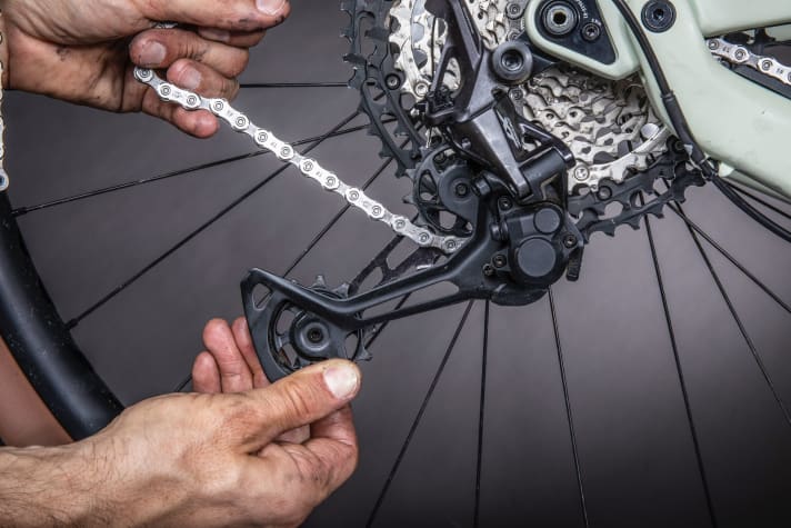 Thread in the chain - pay attention to the bar on the gear cage. 