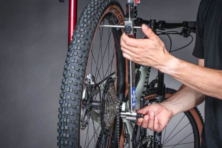 To align the derailleur hanger, the rear wheel must sit straight in the frame and there should be no lateral runout. Then use the alignment gauge to measure the top and bottom of the rim. If the derailleur hanger is straight, the distance between the gauge and the rim should be the same everywhere. If not, bend the derailleur hanger carefully.
