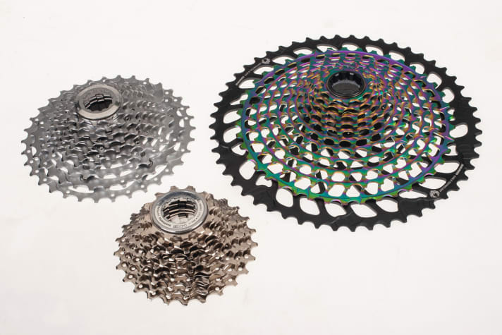 Die Ritzelkassetten variieren je nach Zahl der Kettenblätter erheblich. Ganz links eine universelle XT-Kassette mit 11-34 Zähnen für 3x10-­Schaltungen, darunter eine fein gestufte Rennrad-Kassette, 2x10 mit  12-28 Zähnen. Besonders eindrucksvoll ist die 1x12-Kassette von SRAM (10-52 Zähne, rechts). Elf ihrer Ritzel sind aus einem Block gefräst