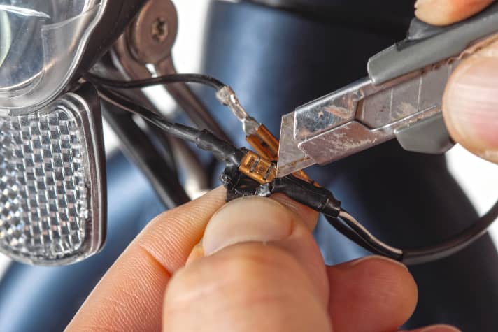 Lösen Sie zuerst die Steckverbindung zum Rücklicht. Oft ist die Stelle mit Schrumpfschlauch isoliert und muss erst etwas mühsam mit einer scharfen Klinge freigelegt werden.