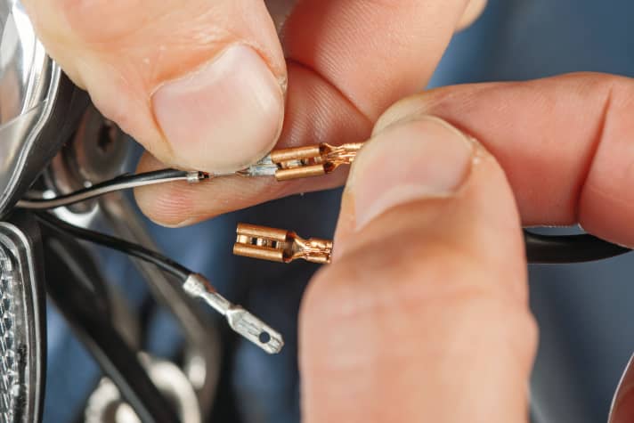 Schieben Sie neuen Schrumpfschlauch auf die Kabelenden und stellen Sie die Steckverbindung zum Rücklicht wieder her. Achtung: Hier müssen Sie die Polung beachten! Das Massekabel ist weiß markiert.