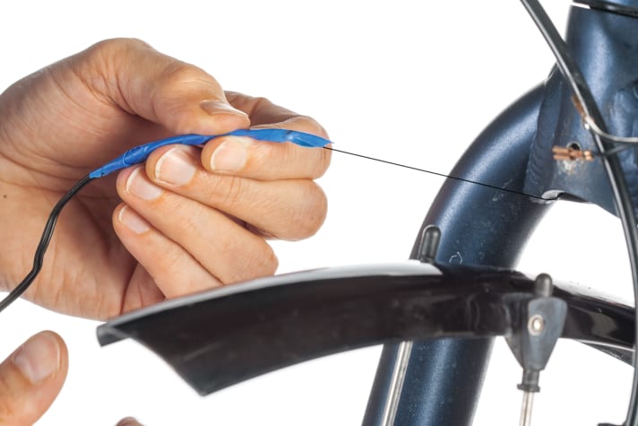 Demontieren Sie die alte Leuchte an der Gabelbrücke. Ziehen Sie das alte Kabel nach oben aus dem Gabelholm, bis der Fadenanfang herausschaut. Trennen Sie Kabel und Faden wieder. Der Faden bleibt auf ganzer Länge im Rohr, um später das neue Lichtkabel an seinen Platz zu bringen.