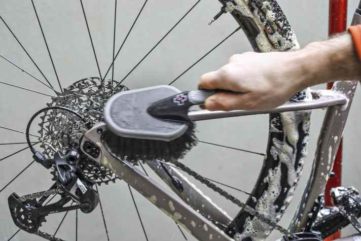 Nachdem der Reiniger eingewirkt ist, löst ihr den restlichen Schmutz mit einer großen Bürste mit langen, weichen Borsten