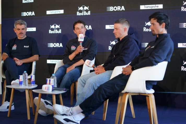 Au centre de l'attention : Florian LIpowitz (avec micro) aux côtés du chef d'équipe Ralph Denk, Remco Evenepoel et Primoz Roglic (de gauche à droite)