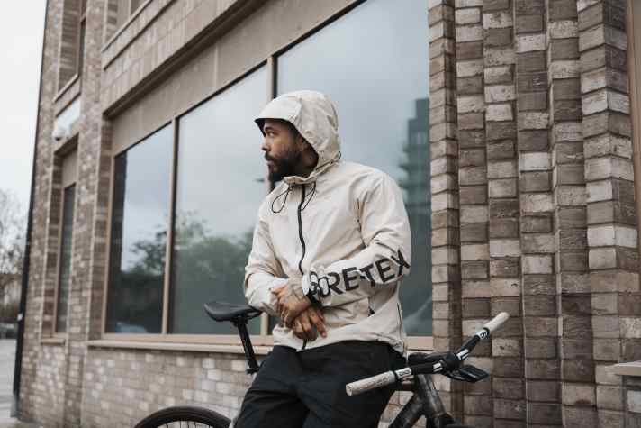 Tech Beige heißt diese Farbvariante. Die Kapuze passt auch über einen Helm und lässt sich verstellen. Beim ersten Verstellversuch ist Suchen angesagt, denn die Mechanismen sind teilweise im Kragen versteckt.