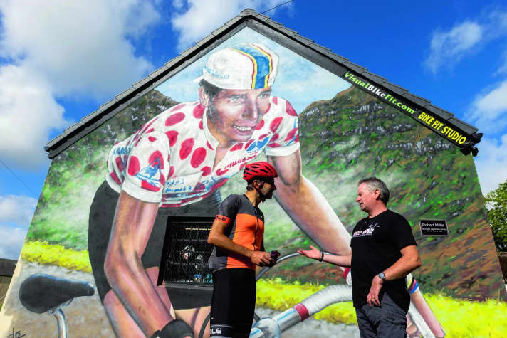 Starkult: Mit Ex-Profi Drew Wilson (rechts) vor seinem Radladen an der Crow Road, auf den er ein großes Graffiti des lokalen Radsporthelden Robert Millar hat sprühen lassen.