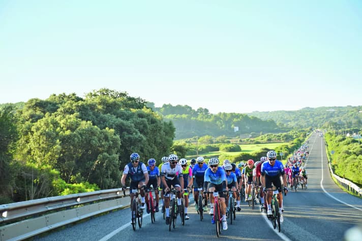 Course en groupe : le peloton roule en formation serrée sur les routes principales fermées d'un côté.
