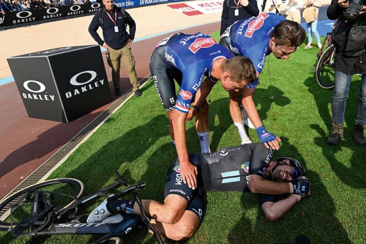 Trost vom Sieger: Geschlagen liegt John Degenkolb auf dem Boden des Radstadions in Roubaix, Mathieu van der Poel (links) und Jasper Philipsen zeigen Mitgefühl.