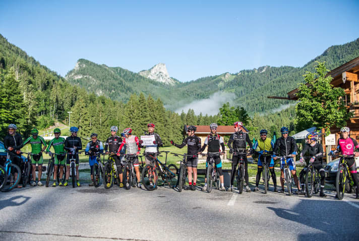   7:00 Uhr, Chiemgau-Arena Ruhpolding: Noch ein rasches Gruppenfoto, dann geht es los. Streckenchef Andi Huber hält das Schild mit dem Standort in die Kamera. Als Fotobeweis. Die Stempelstationen sind ja noch nicht aufgestellt.