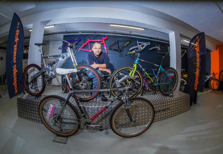  Stefan Utz in den Firmenräumen von Cycleworks, die dekoriert sind mit Kultklassikern. Das C-26 rechts neben ihm ist eine Replika. Das im Vordergrund ist das historische Vorbild.