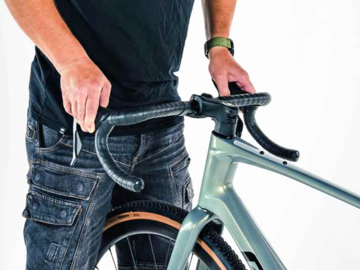 Kontrolle des Lenkers und des Vorbaus: Fasse im Stand den Lenker an den Bremsgriffen, drücke und ziehe abwechselnd.