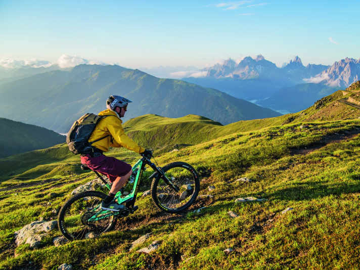 Lush green mountain pastures on one side of the valley, famous Dolomite peaks on the other.