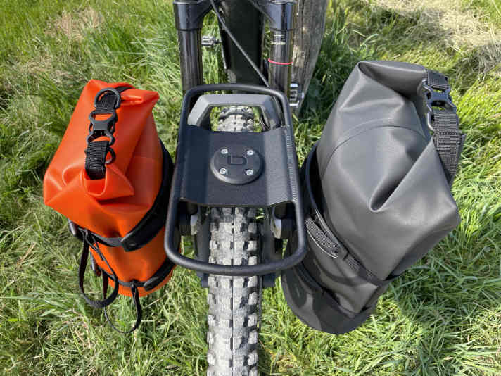 Soit on accroche des sacoches de vélo à la rambarde, soit on utilise le "Spider Cradle" avec des sangles de serrage pour les petits bagages.
