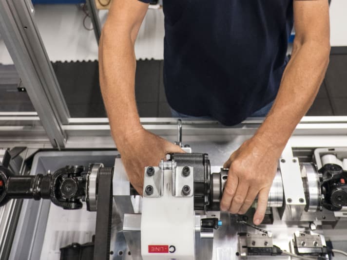 Full control: Each finished gearbox (here in the employee's right hand) undergoes numerous gear and load changes in a high-tech testing machine. In the past, the gearboxes were mounted in a bicycle on a training roller for practical testing.