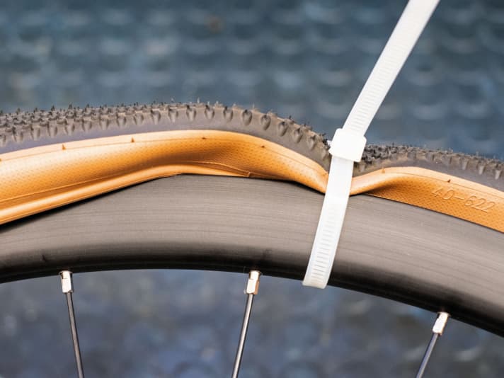 Damit der Wulst während der Montage in der Felgenmitte bleibt, hilft beispielsweise ein Kabelbinder.