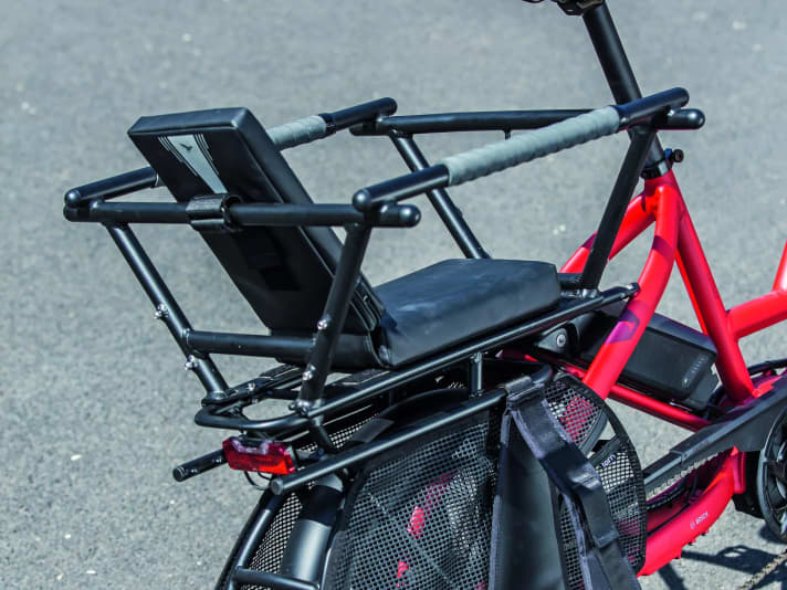 Kindersitz mit Käfig: Das Geländer sowie textile Fußrasten und ein Speichen-Schutzgitter gewährleisten einen sicheren Transport.